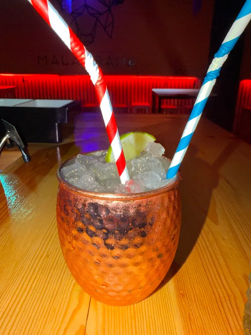 Cóctel con hielo picado y lima en vaso de cobre martillado, con pajitas de rayas
