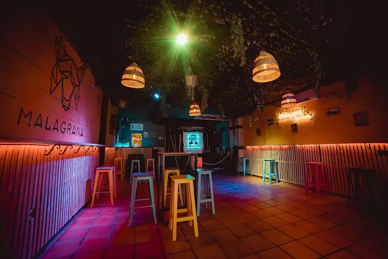 Interior del bar con taburetes de colores, lámparas de mimbre y suelo de barro