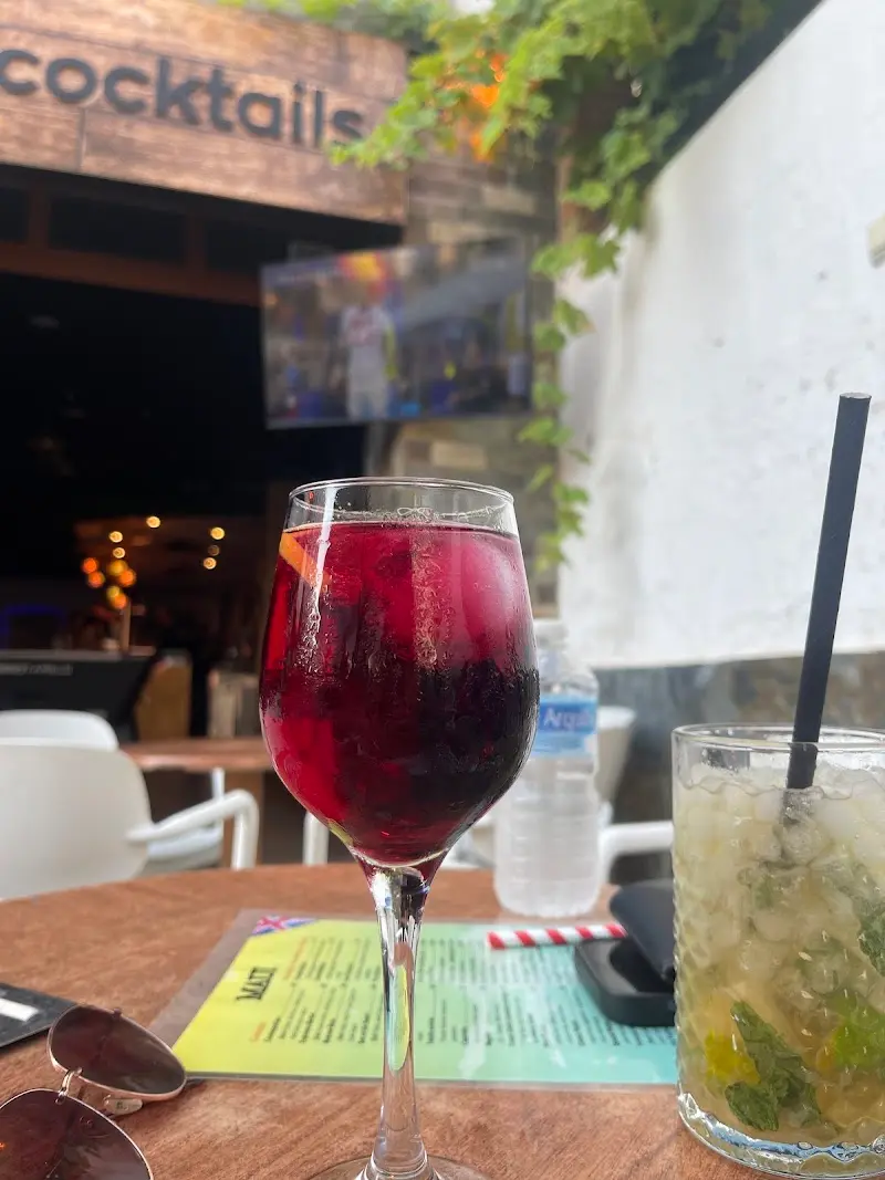 Copa de tinto de verano y mojito sobre la carta, con la barra de cócteles al fondo
