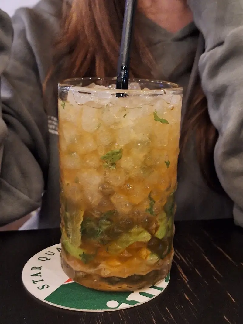 Mojito con hielo picado y hierbabuena en vaso alto sobre un posavasos