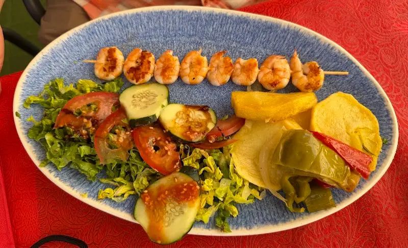 Brocheta de gambas a la plancha con ensalada, patatas y pimientos fritos