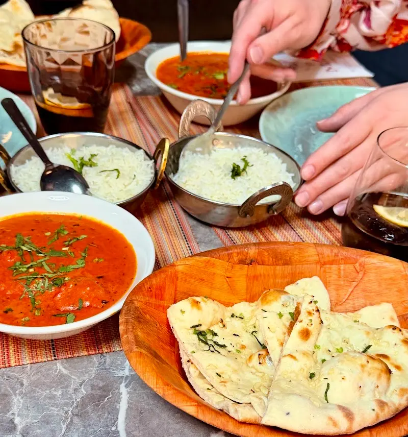 Mesa compartida con curry de tomate, arroz basmati y pan naan en el restaurante indio Mum