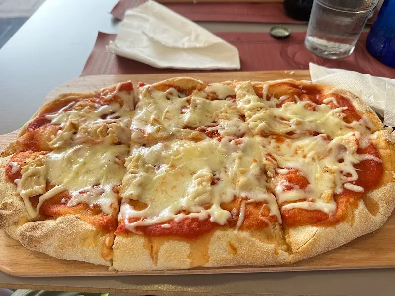 Pizza alargada con tomate y queso fundido servida en tabla de madera