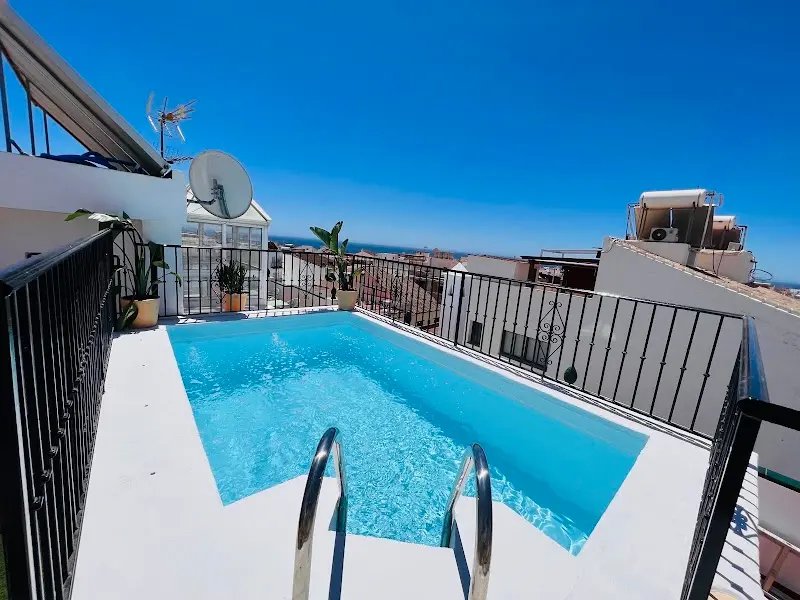 Pequeña piscina en la azotea con barandilla de forja y el mar al fondo