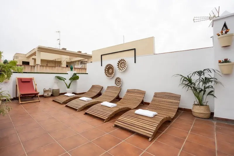 Tumbonas de madera con toallas en la terraza de suelo de barro y paredes blancas