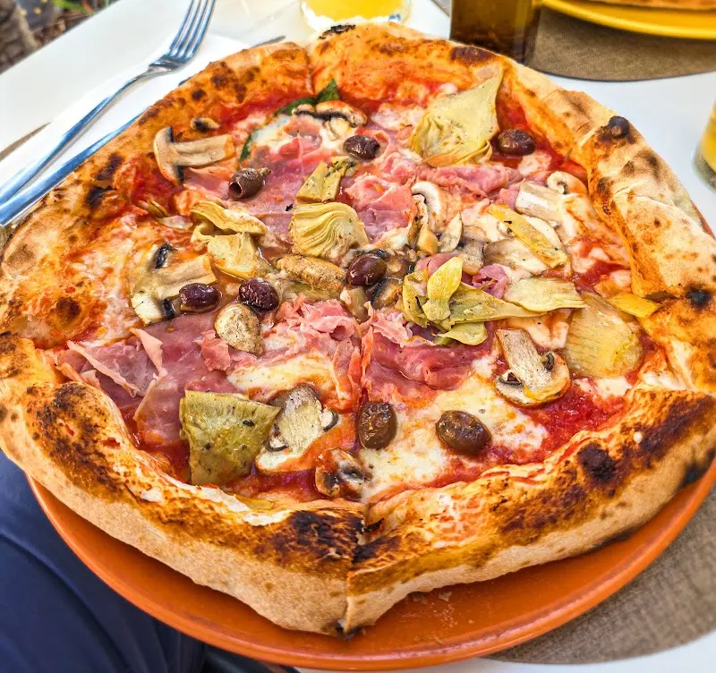 Pizza de horno de leña con jamón, champiñones, alcachofas y aceitunas negras
