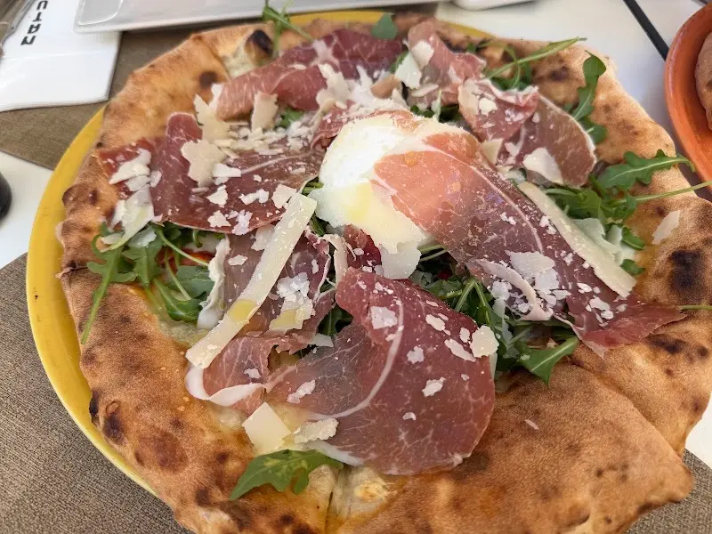 Pizza con jamón curado, rúcula, burrata y lascas de parmesano en Naturale