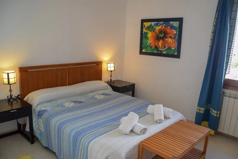 Dormitorio con cama de matrimonio, colcha de rayas, lamparitas y cuadro de una amapola