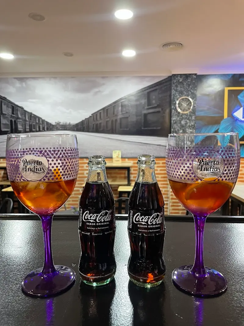 Dos copas de ron con naranja y dos botellines de Coca-Cola sobre la barra