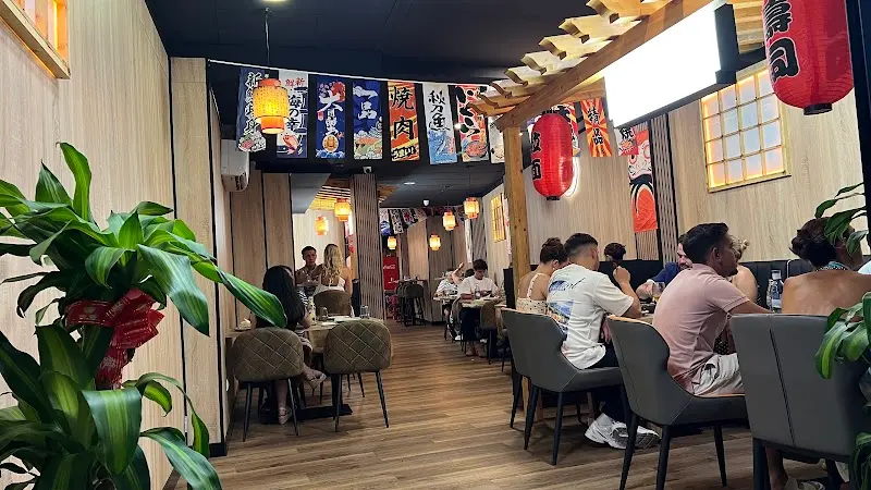 Comedor decorado con farolillos rojos y banderines japoneses, con clientes en las mesas