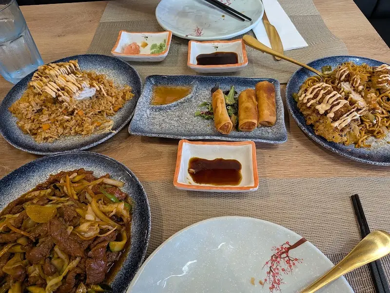 Mesa con arroz frito, fideos salteados, rollitos de primavera y ternera con verduras