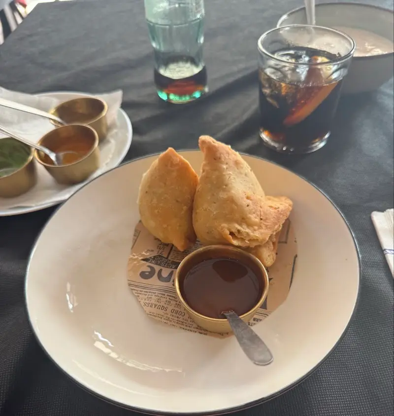 Samosas fritas con salsa de tamarindo y chutneys en cuencos dorados