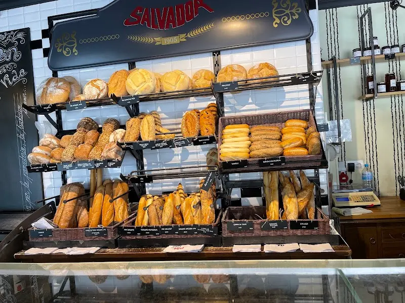 Estanterías con panes de pueblo, baguettes y bollos bajo el letrero de Salvador 1905