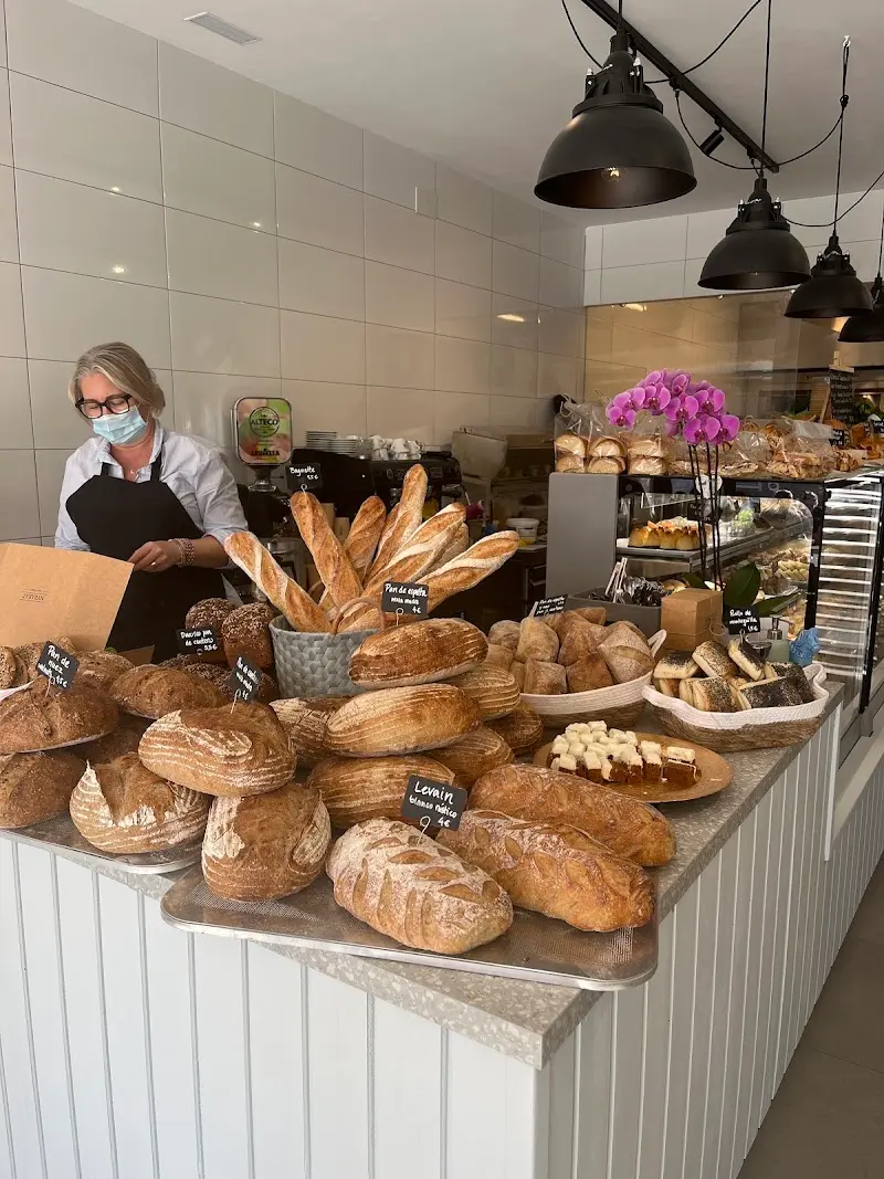 Mostrador con hogazas de masa madre, baguettes y bollería, con carteles de precios