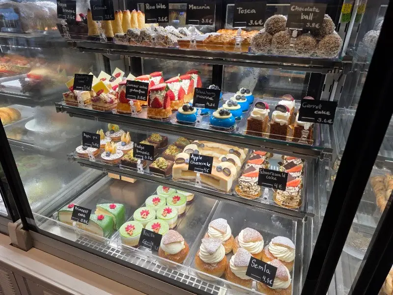 Vitrina de pasteles suecos con precios: semla, mazarín, tosca y tarta de zanahoria