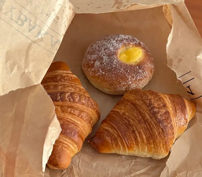 Dos cruasanes y un bollo de crema con azúcar en una bolsa de papel