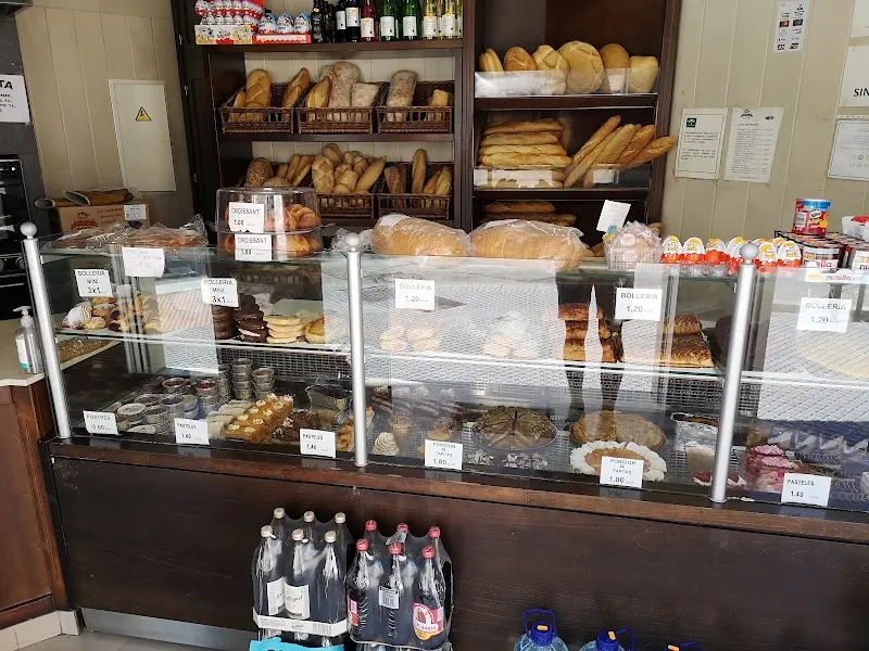 Mostrador con bollería, pan y dulces con precios, y estanterías de barras y hogazas
