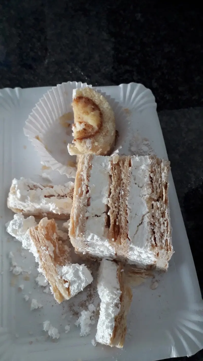 Porciones de milhojas de nata y un dulce de bizcocho sobre una bandeja de cartón