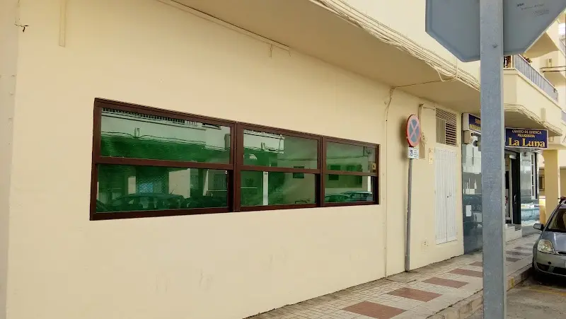 Fachada de un bajo con ventanales de madera y acera en una calle residencial