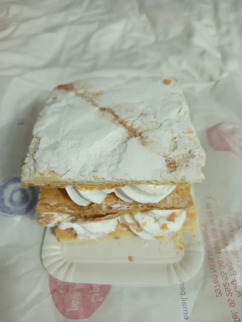Milhojas de crema con azúcar glas y canela sobre papel de la pastelería