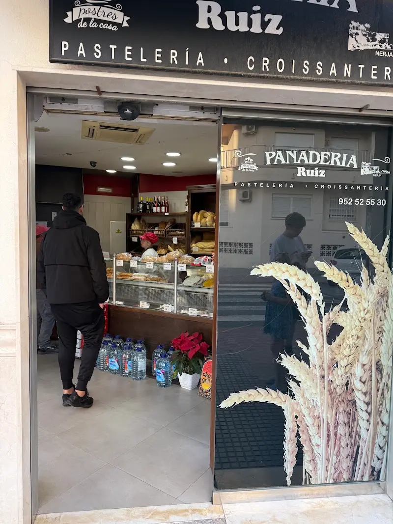 Entrada de la panadería con mostrador de pan y bollería y clientes esperando