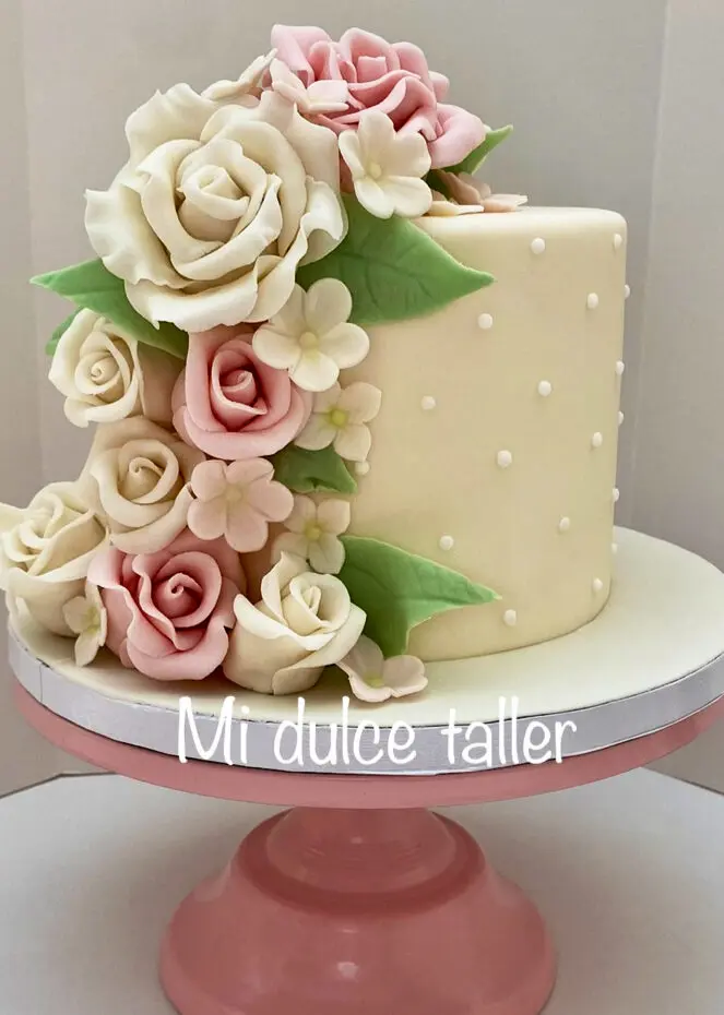 Tarta de fondant color crema decorada con rosas de azúcar blancas y rosas