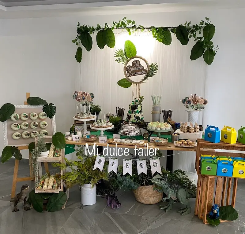 Mesa dulce de primera comunión con tarta, galletas, piruletas y decoración de dinosaurios