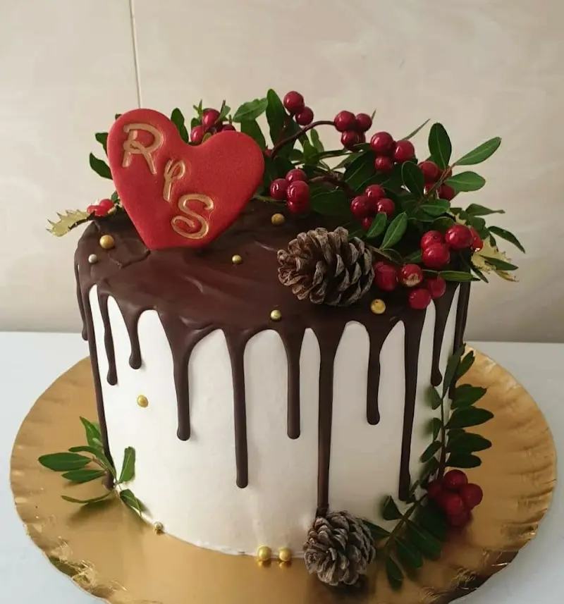 Tarta blanca con chocolate derramado, corazón con iniciales, piñas y frutos rojos