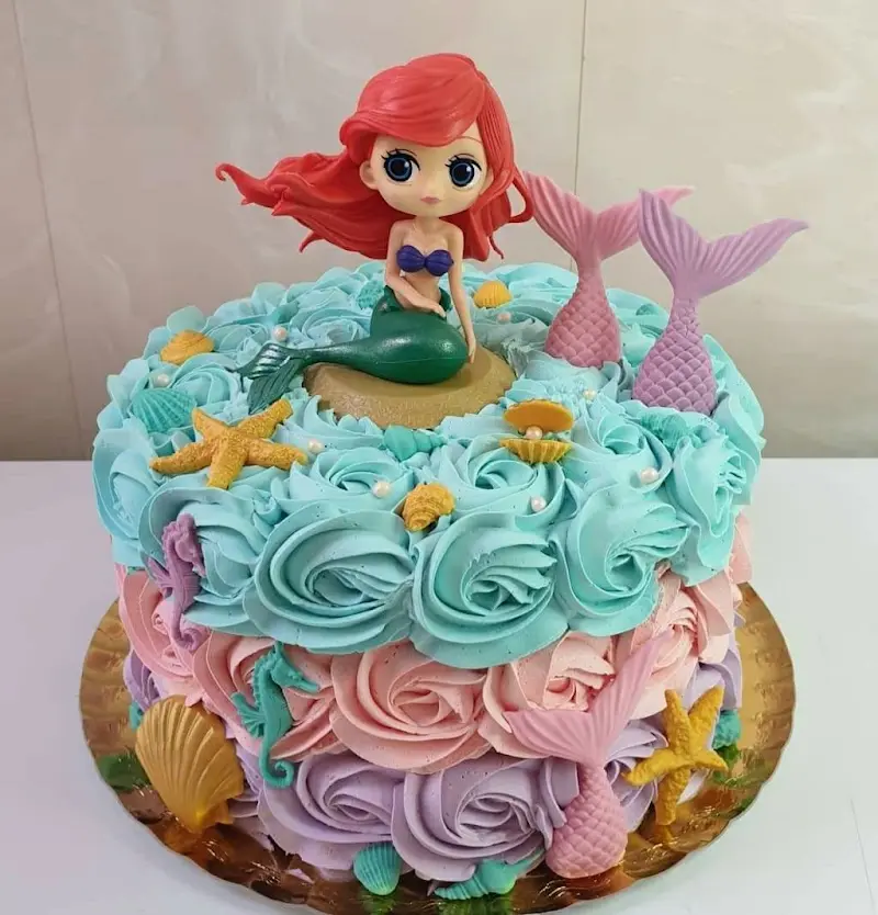 Tarta infantil de sirena con rosas de crema en azul, rosa y lila y estrellas de mar