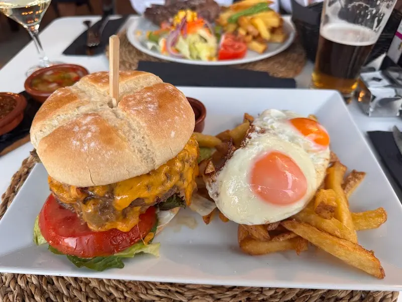 Hamburguesa con queso cheddar y tomate, huevo frito y patatas fritas