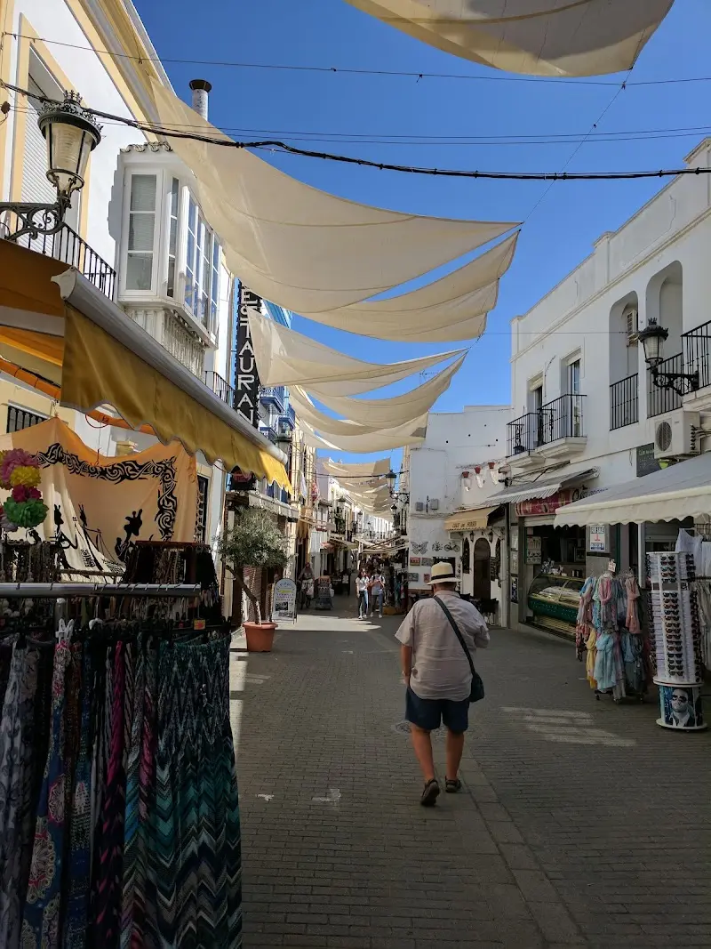 Calle peatonal cercana con toldos de tela, tiendas de ropa y paseantes