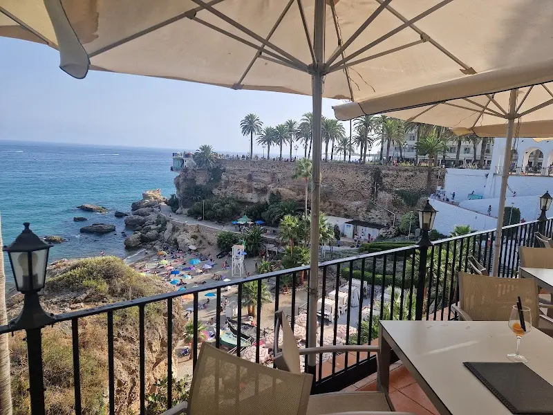 Terraza con vistas al mar, la playa con sombrillas y el Balcón de Europa al fondo