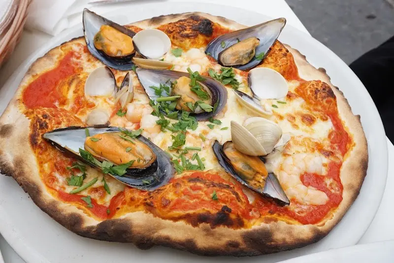 Pizza de marisco con mejillones, almejas, gambas y perejil