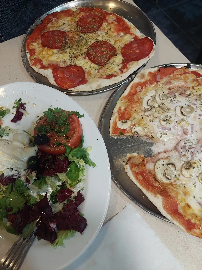 Pizza de chorizo, pizza de jamón y champiñones y ensalada mixta en la mesa