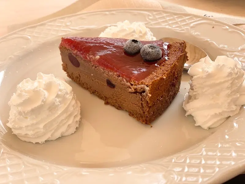 Porción de tarta con cobertura de frutos rojos, arándanos y nata montada