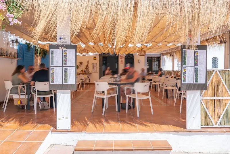 Terraza con techo de cañizo y cartas expuestas en los pilares de la entrada