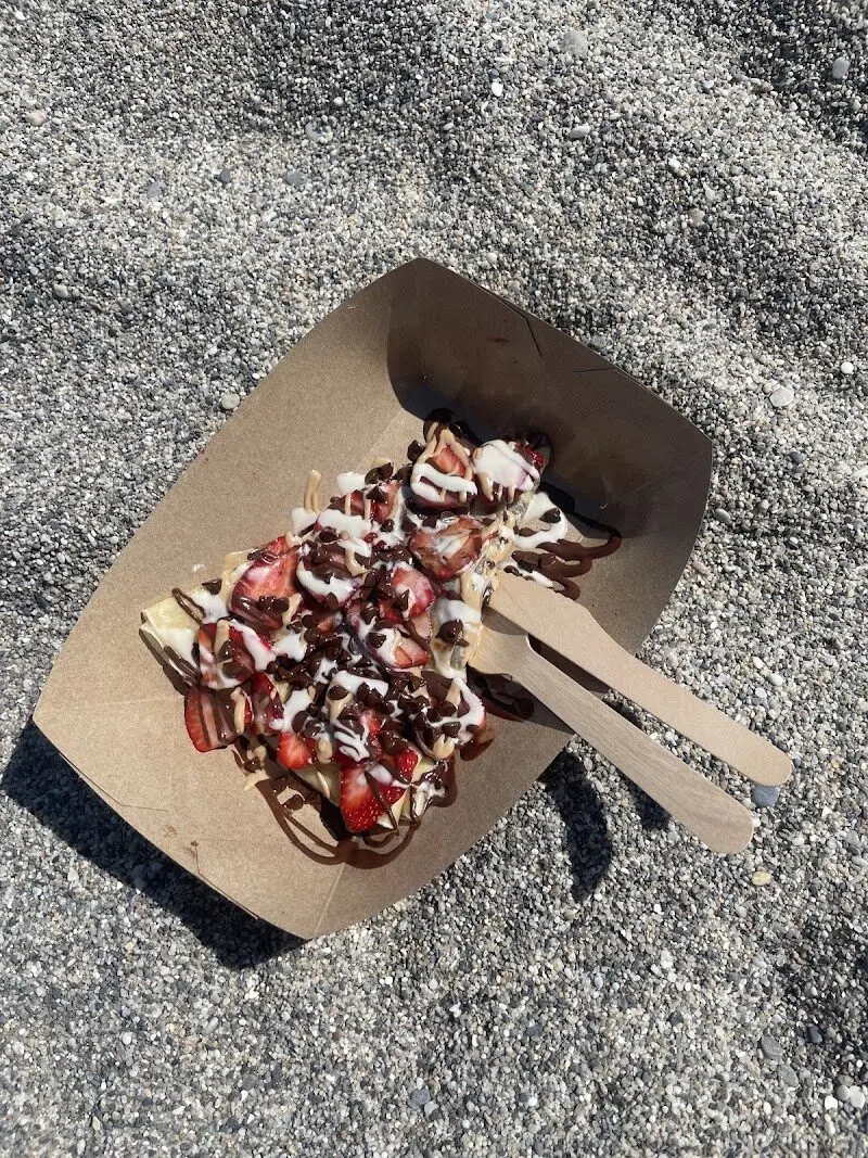 Crepe con fresas, chocolate y nata en una bandeja de cartón sobre la arena de Burriana