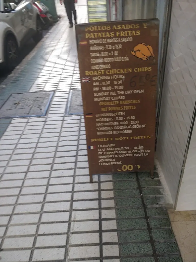 Pizarra en la acera con horario de pollos asados y patatas fritas en cuatro idiomas