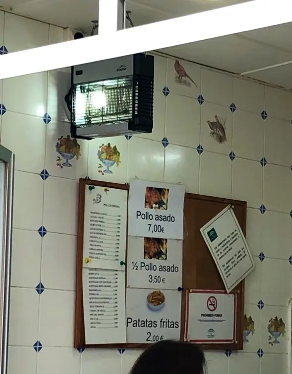 Carteles con precios: pollo asado 7 €, medio pollo 3,50 € y patatas fritas 2 €