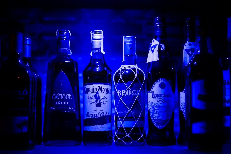 Botellas de ron alineadas en la estantería bajo luz azul