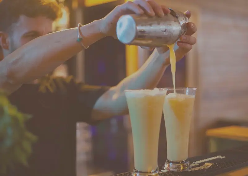 Bebida cremosa servida desde la coctelera en dos vasos altos