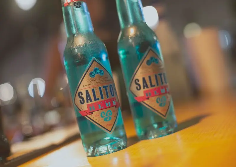 Dos botellas de cerveza Salitos Blue de color azul sobre la barra de madera