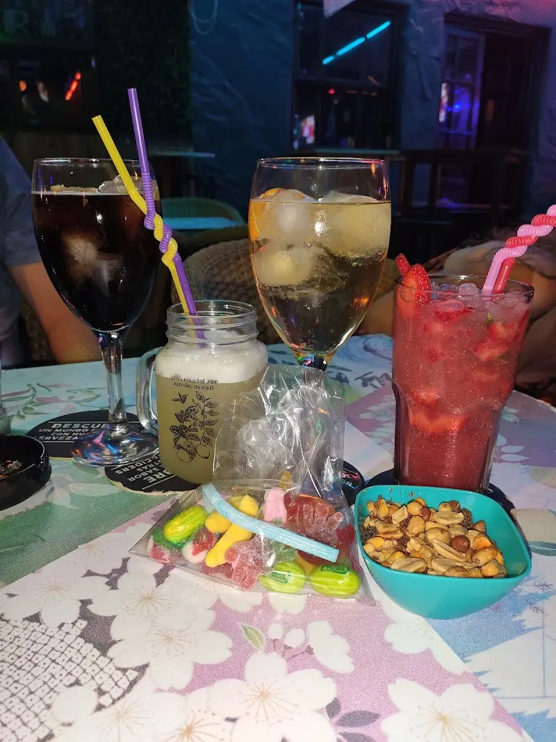 Refrescos, cerveza en jarra y cóctel de fresa con frutos secos y golosinas sobre la mesa