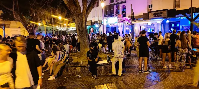 Plaza abarrotada de gente de noche junto a los bares de copas y los árboles iluminados