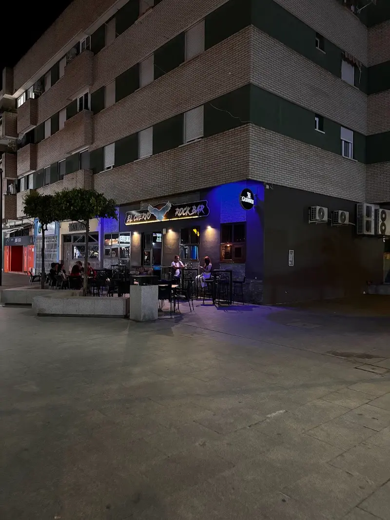 Fachada de El Cuervo Rock Bar de noche, con terraza en la esquina de un edificio de ladrillo