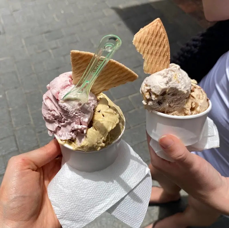 Dos tarrinas de helado con barquillo, una de fresa y pistacho, en la calle