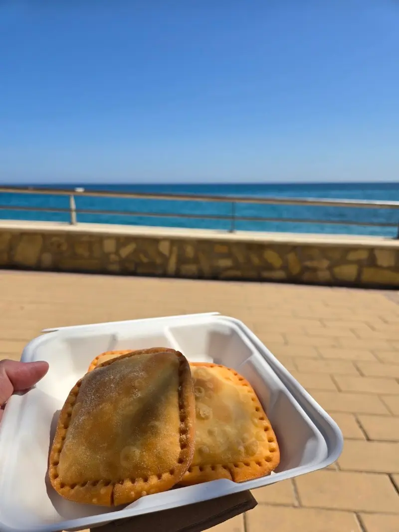 Dos empanadas fritas en una caja para llevar frente al mar azul