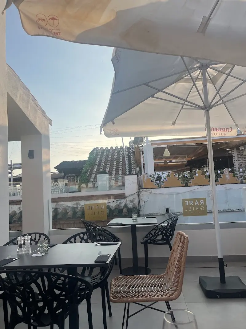 Terraza en la azotea con sombrillas y mesas negras sobre los tejados de Nerja al atardecer