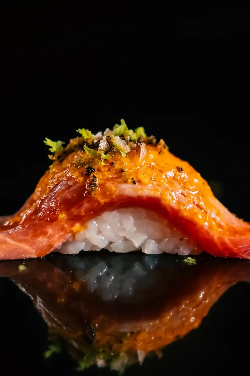 Nigiri de pescado rojo flambeado con salsa anaranjada y ralladura de lima