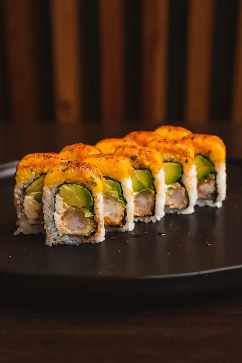 Piezas de uramaki con aguacate y langostino gratinadas en un plato oscuro